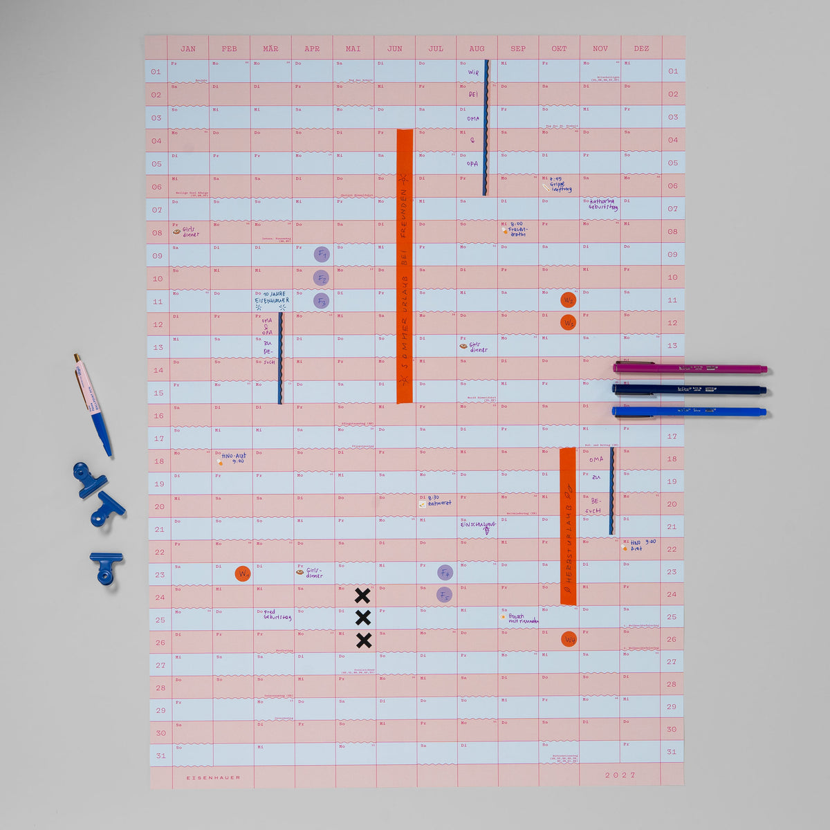 Wandkalender 2027 im Hochformat mit Washi-Tape, Stickern, handschriftlichen Einträgen, blauen Klammern und Stiften