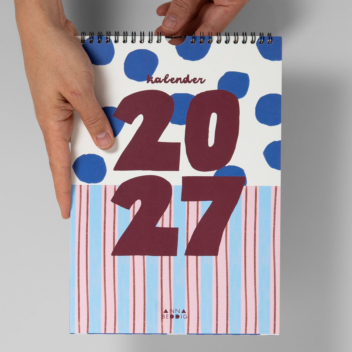 Monatskalender 2027 im DIN-A4-Format zum Größenvergleich in zwei Händen gehalten