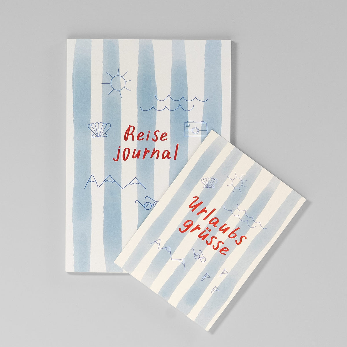 Reisejournal neben der Postkarte „Urlaubsgrüße“ im passenden blau-weißen Streifenmuster