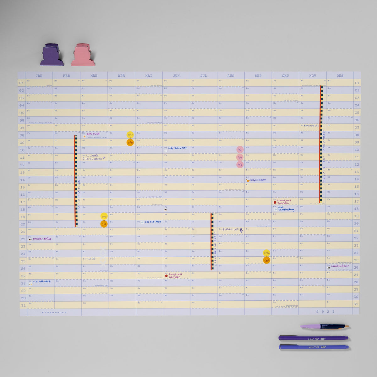 Wandkalender 2027 im Querformat mit handschriftlichen Einträgen, Stickern, Washi-Tape, Klammern und Stiften