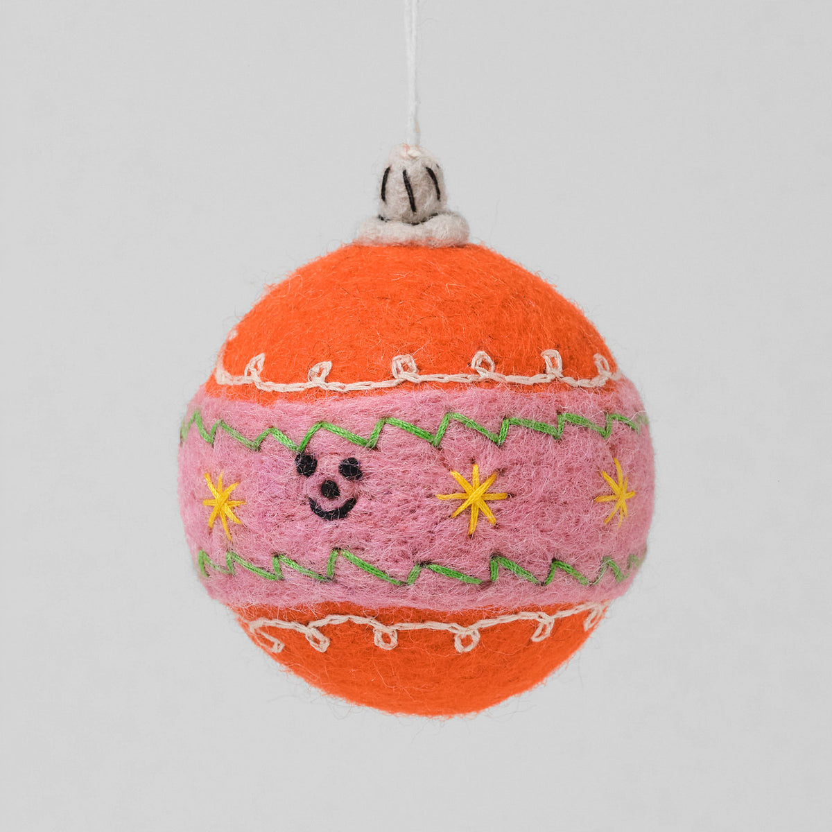 Wrap Filzanhänger Christbaumkugel: orange Filzkugel mit rosa Band, Stickerei, gelben Sternen und lächelndem Gesicht